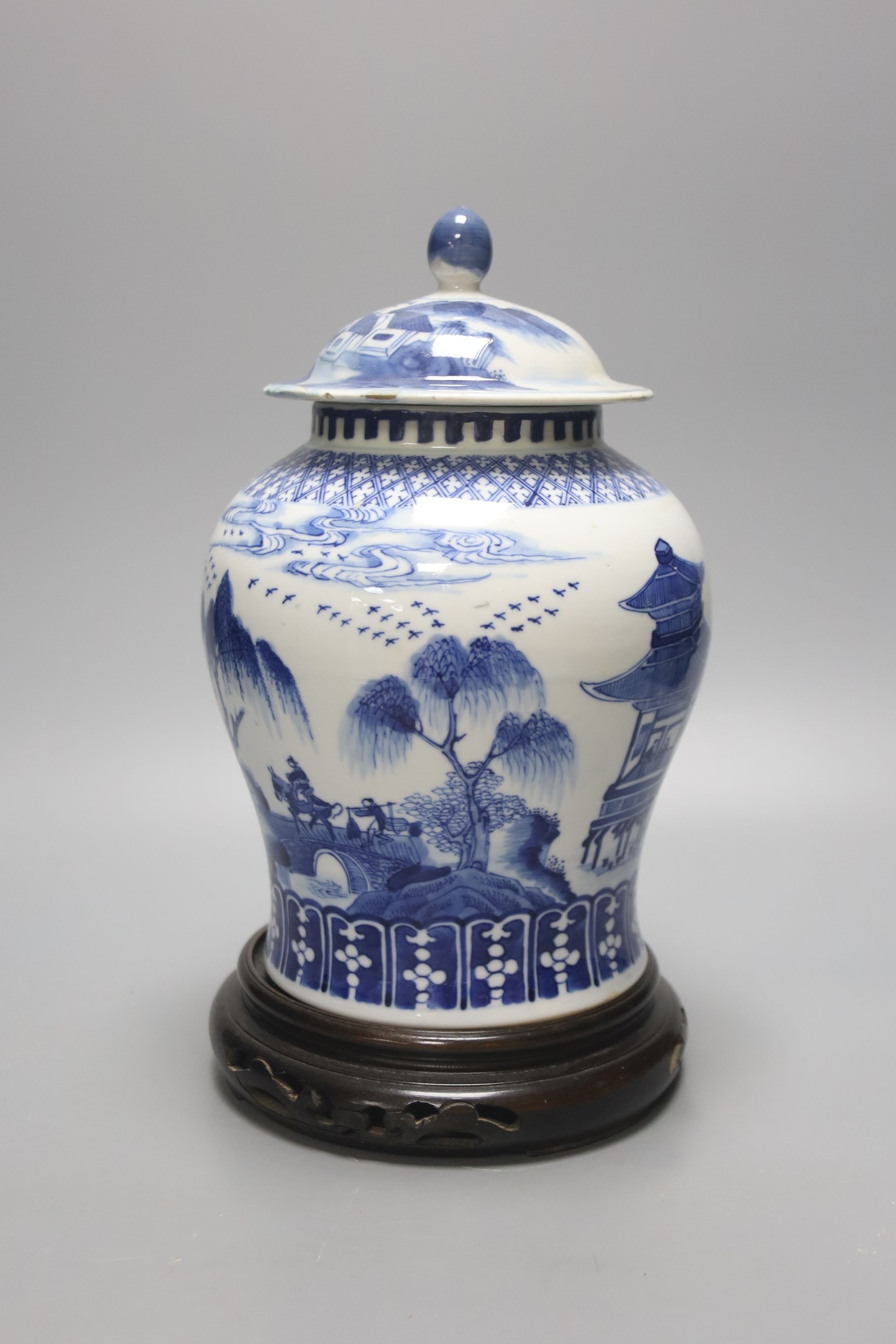 A late 19th / early 20th century Chinese blue and white landscape jar and cover, wood stand 30cm total height